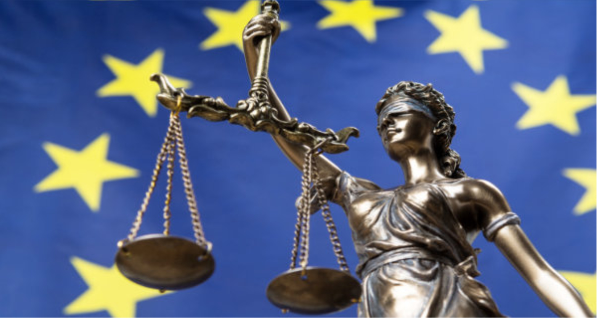 Die Statue von Gerechtigkeit Themis oder Justitia, die Göttin mit verbundenen Augen von Gerechtigkeit, im Hintergrund die europäische Flagge | Adobe Stock | respiro888 | 224808539 